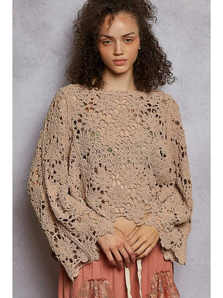 A woman wearing a loose fit crochet top in a soft latte color with a textured chenille design.