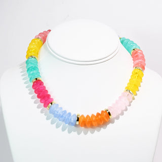 A colorful necklace with multi-colored resin beads displayed on a white stand.