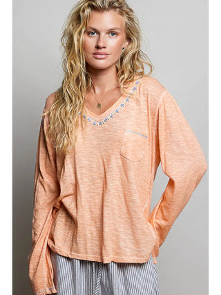Lightweight coral peach knit top with hand-stitched V-neckline and front pocket.