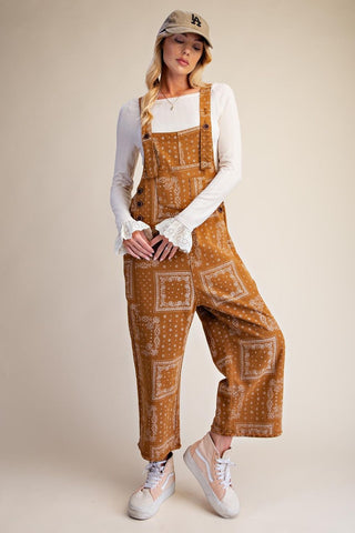 Model wearing camel-colored bandana print washed twill overalls with a relaxed fit.