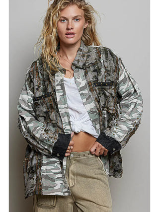 A long sleeve shirt with plaid and camo patterns, featuring contrast studs, worn by a model with beige pants.