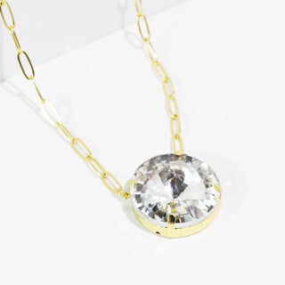 Gold necklace with a round clear pendant on a delicate link chain.