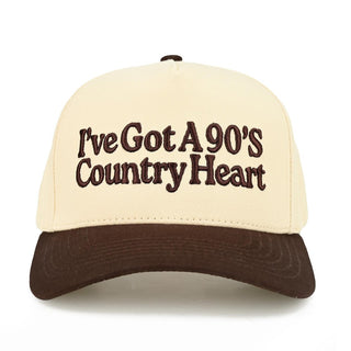 Canvas baseball cap in cream with brown brim and 'I've Got A 90's Country Heart' embroidered in brown.