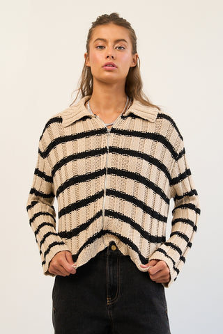 A ribbed stripe knit zip-up sweater in brown and black, worn by a model.