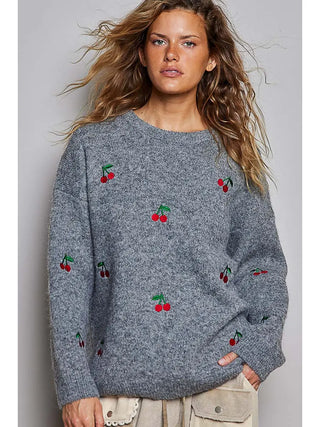 A grey oversized sweater with cherry embroidery and a crew neckline.