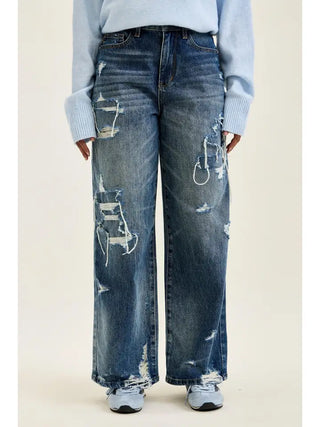 Baggy jeans in vintage sandstone blue with distressed detailing worn by a model.