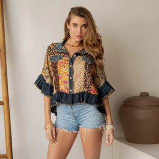 A woman wearing a distressed denim crop jacket in latte color with a button-up front and cropped fit.