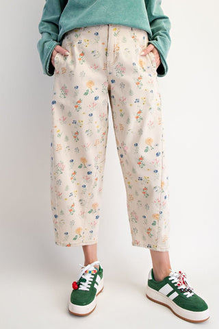 A person wearing floral-patterned pants with green sneakers.
