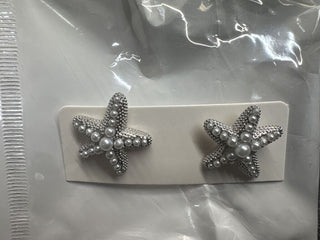 Starfish-shaped earrings in silver tone with pearl embellishments on a white card.