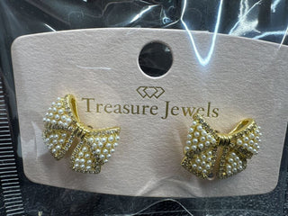 Gold bow earrings with pearl accents on a display card from Treasure Jewels.