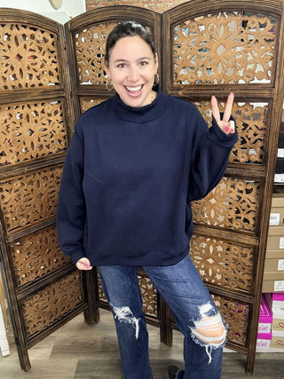 A person wearing a navy sweatshirt with a relaxed fit and crew neckline.