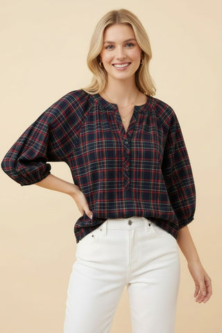 Woman wearing a navy plaid popover blouse with long sleeves and a henley neckline.