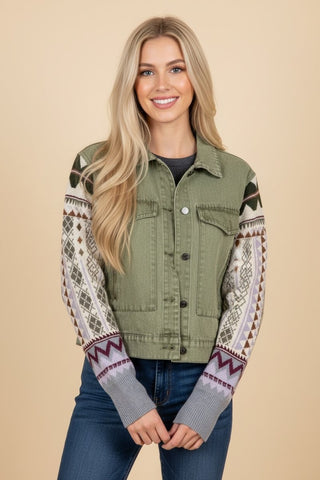 A dark sage utility jacket with patterned knit sleeves, worn by a model with long blonde hair.